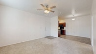 This efficient and thoughtfully designed 1-bedroom, 1-bathroom unit offers a comfortable single-floor layout. The open living and dining area is finished with neutral-toned carpet and features a ceiling fan with light kit, creating a bright and airy atmosphere. French doors lead directly to the private patio, which is enclosed by a black metal railing and offers views of the surrounding community.

The galley-style kitchen is outfitted with rich dark wood cabinetry, light stone-look countertops, a stainless sink, and a full suite of black appliances including a range, over-the-range microwave, and refrigerator. Wood-look vinyl flooring runs throughout the kitchen, adding warmth and easy maintenance. A pendant light illuminates the adjacent dining area.

The generously sized bedroom is carpeted and filled with natural light from multiple windows, and includes a ceiling fan. A dedicated walk-in closet with built-in shelving and hanging rods provides ample storage.

The bathroom features a full soaking tub and shower combo with built-in wall shelving, complemented by a dark wood overhead cabinet for additional storage. Wood-look flooring ties the space together with a clean, cohesive finish throughout the unit.