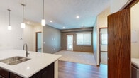 This single-floor residence offers a thoughtfully designed layout that balances comfort and functionality. The open-concept living and dining area features a combination of rich hardwood-style flooring and plush carpeting, recessed lighting, and a large window with vertical blinds that allows ample natural light to fill the space. A direct-access exterior door adds convenience to the living area.

The kitchen is a standout feature, equipped with rich dark espresso cabinetry extending to the ceiling for generous storage, stainless steel appliances including a refrigerator, range, and built-in microwave, and a sleek white countertop peninsula with an undermount sink. Pendant lighting above the peninsula enhances both the aesthetics and functionality of the space.

The bedrooms are carpeted for comfort, each featuring ceiling fans, vertical-blind windows for natural light and privacy, and solid six-panel wood doors. The rooms offer a clean, neutral palette suitable for a variety of furnishing styles.

Two full bathrooms serve the residence, both finished with dark espresso vanity cabinetry, white countertops, large mirrors, and hardwood-style flooring. One bathroom includes a full tub-shower combination, providing added versatility. Throughout the unit, consistent wood-tone trim and fixtures tie the design together cohesively.