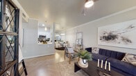 This well-appointed single-floor residence offers a thoughtfully designed open-concept layout that seamlessly connects the living, dining, and kitchen areas. The living room is a welcoming space highlighted by crown molding, a ceiling fan, and large windows that invite natural light and offer views of the surrounding greenery. Light-toned herringbone-patterned flooring runs throughout, lending a clean and modern aesthetic to the entire unit.

The galley-style kitchen is efficiently laid out with crisp white cabinetry, white quartz countertops, subway tile backsplash, and a full suite of stainless steel appliances, including a refrigerator, microwave, dishwasher, and electric range. A pass-through opening connects the kitchen to the dining area, enhancing the sense of openness and making it ideal for entertaining.

The dining area features a mirrored accent wall that amplifies light and space, while a decorative pendant light adds a touch of elegance. The bedrooms are comfortably sized, each with windows that provide natural light and ceiling fans for comfort. The bathroom is clean and functional, featuring a white vanity with brushed nickel hardware, a tub-shower combination, and light wood-look flooring. Overall, the space delivers a bright, modern, and cohesive living environment.