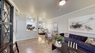 This well-appointed single-floor residence offers a thoughtfully designed open-concept layout that seamlessly connects the living, dining, and kitchen areas. The living room is a welcoming space highlighted by crown molding, a ceiling fan, and large windows that invite natural light and offer views of the surrounding greenery. Light-toned herringbone-patterned flooring runs throughout, lending a clean and modern aesthetic to the entire unit.

The galley-style kitchen is efficiently laid out with crisp white cabinetry, white quartz countertops, subway tile backsplash, and a full suite of stainless steel appliances, including a refrigerator, microwave, dishwasher, and electric range. A pass-through opening connects the kitchen to the dining area, enhancing the sense of openness and making it ideal for entertaining.

The dining area features a mirrored accent wall that amplifies light and space, while a decorative pendant light adds a touch of elegance. The bedrooms are comfortably sized, each with windows that provide natural light and ceiling fans for comfort. The bathroom is clean and functional, featuring a white vanity with brushed nickel hardware, a tub-shower combination, and light wood-look flooring. Overall, the space delivers a bright, modern, and cohesive living environment.