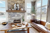 This contemporary residential space showcases a harmonious blend of rustic and modern design elements. The living area is anchored by a stunning floor-to-ceiling stone fireplace, complemented by large windows that flood the room with natural light. The kitchen boasts sleek stainless-steel appliances and dark wood cabinetry, set against a backdrop of stone walls and patterned tile flooring. A spacious fitness center features top-of-the-line equipment and expansive windows offering outdoor views. The complex also includes a welcoming entrance with glass doors flanked by potted olive trees, and various seating areas for relaxation and socializing. Throughout the space, attention to detail is evident in the carefully curated furnishings, artwork, and lighting fixtures, creating an upscale and inviting atmosphere for residents and guests alike.