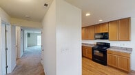 This well-appointed two-bedroom, two-bathroom residence at 101 Clifton Park Cir in Wilmington, Delaware offers a comfortable and functional single-floor layout. The kitchen is equipped with warm honey-toned wood cabinetry, granite-style countertops, hardwood-style flooring, recessed lighting, and black appliances including a refrigerator, range, microwave, and dishwasher. A pass-through window connects the kitchen to the adjacent living area, enhancing the open feel of the shared space. The living room is spacious and carpeted, anchored by a sleek built-in fireplace that serves as a focal point, creating a cozy atmosphere. Sliding glass doors lead from one of the rooms to a private balcony with outdoor views of the surrounding community. Both bedrooms are generously sized, featuring plush carpeting and ceiling fans with light fixtures. The primary bedroom is particularly spacious, with a double-door closet and direct access to an en-suite bathroom. Each bathroom includes a full tub-shower combination with clean white finishes and chrome fixtures. The overall design is bright and neutral throughout, offering a move-in-ready canvas well-suited for a variety of living arrangements.