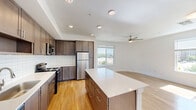 Located in Austin's vibrant 78702 zip code, this single-floor, three-bedroom, two-bathroom home offers a well-designed layout with a clean, modern aesthetic throughout. Light hardwood-style flooring flows seamlessly across all living areas, complemented by crisp white walls and ceiling fans in every room.

The kitchen is a standout feature, equipped with stainless steel appliances including a refrigerator, electric range, and microwave. Rich dark-toned cabinetry extends floor to ceiling, providing generous storage, while a classic white subway tile backsplash adds texture and contrast. A large central island with a white quartz-style countertop offers additional prep space and opens directly to the living area, which benefits from natural light through a large window.

The three bedrooms are bright and airy, each featuring hardwood-style flooring, ceiling fans, and large windows that invite natural light and views of the surrounding neighborhood. The spacious primary bedroom offers a comfortable retreat with ample room.

Both bathrooms reflect the home's contemporary style, featuring dark wood vanities with white countertops and tile-surround tub-shower combinations. Two closets provide practical storage solutions. The overall ambiance is clean, modern, and move-in ready, ideal for those seeking comfortable urban living in East Austin.