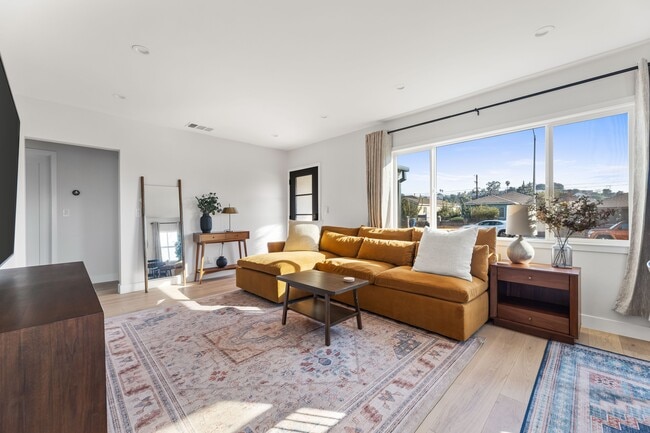 Living room with West Elm furniture, natural sunlight, and large TV flatscreen. - 1823 N Ditman Ave