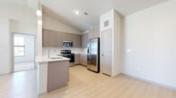 This single-floor residence showcases a cohesive, contemporary design highlighted by a neutral color palette and quality finishes throughout. The kitchen serves as a central feature, equipped with stainless steel appliances including a French door refrigerator, electric range, over-the-range microwave, and dishwasher. Taupe shaker-style cabinetry extends to the ceiling, paired with white countertops and a subway tile backsplash. A peninsula with a built-in sink offers additional workspace and casual seating potential. Light wood-style flooring flows throughout the main living and kitchen areas, contributing to a bright, open feel.

The bedrooms are carpeted and generously sized, each featuring a ceiling fan and a window that allows natural light to filter in. Two walk-in closets provide substantial storage, each outfitted with multi-tiered wire shelving systems and carpeted floors.

The bathrooms reflect the same refined aesthetic, with taupe cabinetry, white countertops, and brushed nickel fixtures. The primary bathroom includes a glass-enclosed walk-in shower with tile surround, while the secondary bathroom offers a full soaking tub with a tiled surround, cabinetry, and an overhead vanity mirror.