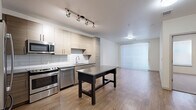 Located at 1920 S University Blvd in Denver, CO, this well-appointed one-bedroom, one-bathroom residence offers a thoughtfully designed single-floor layout with modern finishes throughout. The open-concept kitchen and living area serves as the heart of the home, featuring wood-look plank flooring, crisp white walls, and an abundance of natural light from large windows fitted with roller shades. The kitchen is outfitted with stainless steel appliances — including a French door refrigerator, gas range, built-in microwave, and dishwasher — complemented by two-tone flat-front cabinetry, a white subway tile backsplash, and a dark quartz countertop island perfect for casual dining or food preparation. Track lighting illuminates the space with a clean, contemporary feel. The living area flows seamlessly from the kitchen, offering an open and airy atmosphere. The bedroom is carpeted for comfort and features two windows with natural light, a ceiling fan, and access to a spacious walk-in closet with built-in shelving. The bathroom is finished with large-format white floor tiles, a tub/shower combo with full tile surround, and a wood-toned vanity with a dark countertop. A dedicated laundry area with a stacked washer and dryer adds everyday convenience.