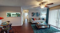 This single-floor residence offers a well-organized layout designed for comfortable everyday living. The living room serves as the heart of the home, featuring rich hardwood-style flooring, a ceiling fan with light fixture, a cozy fireplace, and a sliding glass door that floods the space with natural light. The dining area is distinguished by a bold teal accent wall and a pass-through window that connects seamlessly to the kitchen, creating an open, communicative flow between spaces. The galley-style kitchen is thoughtfully appointed with white cabinetry, granite-style countertops, a grey tile backsplash, and black appliances including a refrigerator, electric range, microwave, and dishwasher. Two bedrooms provide comfortable retreats; the primary bedroom features a vibrant orange accent wall, plush carpeting, a ceiling fan, and a large window with ample natural light, while the secondary bedroom offers a quieter, neutral palette with carpet flooring and its own ceiling fan. The bathroom is well-equipped with a granite-topped vanity, a tub-shower combination, and hardwood-style flooring. A dedicated in-unit laundry room with full-size washer and dryer adds a practical convenience. Throughout the home, a cohesive color palette of teal, orange, and white lends an energetic and inviting ambiance.