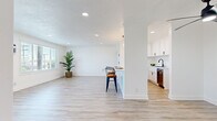 Located at 10720 Shellyfield Rd in Downey, CA, this thoughtfully updated 3-bedroom, 2-bathroom unit offers a clean, modern aesthetic throughout. Light wood-style flooring runs continuously across all rooms, complementing the crisp white walls and creating a bright, cohesive feel. The open-concept living room is bathed in natural light from large windows with views of the surrounding greenery, accented by recessed lighting and a textured ceiling.

The kitchen is well-appointed with white shaker cabinetry, black hardware, white subway tile backsplash, and stainless steel appliances including a range, over-the-range microwave, and dishwasher. A peninsula with bar seating connects the kitchen seamlessly to the living area, making it ideal for everyday living and entertaining.

The spacious primary bedroom features a ceiling fan with light, a window unit, and ample room to furnish comfortably. Additional bedrooms are generously sized and share a similar clean, minimalist design. Each room includes closet access via the hallways.

The bathrooms are elegantly finished with marble-look tile surrounds on the tub/shower combo, sleek sliding glass doors with black framing, white vanity cabinetry, and quartz countertops with a matte black faucet. Two closets provide added storage throughout the unit.