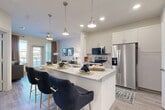 Located at 7200 Chase Oaks Blvd in Plano, TX, this well-appointed single-floor residence offers a smart and efficient layout across one bedroom, one bathroom, and a dedicated laundry area. The open-concept kitchen and dining area serves as the heart of the home, showcasing granite countertops, white shaker cabinetry, stainless steel appliances — including a French door refrigerator, electric range, and built-in microwave — and a large center island with bar seating illuminated by pendant lighting. Wood-look flooring flows throughout, adding warmth and continuity. The living room is bright and inviting, benefiting from large windows that usher in natural light and provide outdoor views, along with a door leading to a private exterior space. The bedroom offers a comfortable retreat with natural light from dual windows and generous closet space supported by two dedicated closets. The bathroom is finished with a granite vanity, a glass-enclosed walk-in shower with tile surround, and wood-look flooring. A separate laundry area adds everyday convenience. Clean lines, neutral tones, and quality finishes throughout create a cohesive and modern living environment.