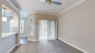 Located at 3225 Woodland Park Dr in Houston, Texas, this well-appointed 2-bedroom, 1-bathroom residence offers a comfortable and functional single-floor layout. Neutral warm-toned walls and crisp white crown molding and baseboards carry throughout, creating a cohesive and clean aesthetic.

The living area features plush carpeting, a ceiling fan, and sliding glass doors dressed with vertical blinds that open to an outdoor area, allowing for generous natural light. A side window further brightens the space.

The galley-style kitchen is outfitted with light gray cabinetry, white quartz countertops, a stainless steel sink, and stainless steel appliances including a refrigerator and range. Wood-look luxury vinyl plank flooring ties the kitchen and hallways together seamlessly.

The primary bedroom is a comfortable size and features a tray ceiling with a ceiling fan, a large window with outdoor views, and soft carpeting. The second bedroom also offers carpeting and elegant crown molding. A dedicated closet provides additional storage.

The bathroom is finished with marble-look tile surrounding the tub/shower combo, complemented by a white vanity and wood-look flooring. A separate laundry area includes washer and dryer hookups and shelving for added convenience.