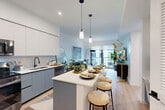 Located at 501 NW Seventh Ave in Fort Lauderdale, FL, this thoughtfully designed one-bedroom, one-bathroom residence offers a modern, open-concept floor plan across a single level. Light wood flooring flows throughout, complementing the bright, neutral palette that enhances the sense of space.

The combined kitchen, dining, and living area serves as the heart of the home. The contemporary kitchen features two-tone cabinetry — white upper cabinets paired with slate-blue lower units — accented by a subway tile backsplash, white quartz countertops, a black matte faucet, and a full suite of stainless steel appliances including a range, microwave, and dishwasher. A peninsula island with seating provides a practical dining and gathering space, while pendant lighting adds a refined touch overhead.

The living area is anchored by floor-to-ceiling sliding glass doors that open to a private balcony, allowing abundant natural light and outdoor views. The bedroom offers a comfortable, well-proportioned retreat with large windows overlooking lush surroundings. Two closets and an in-unit laundry area provide excellent storage and convenience. The bathroom and hallway complete this efficiently organized, stylish residence ideal for modern urban living.