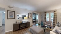 Located at 1900 Tree Mountain Parkway in Stone Mountain, Georgia, this single-floor, 2-bedroom, 2-bathroom residence offers a well-organized and comfortable layout. The living room features wood-style flooring, a textured ceiling, and an open sightline into a separate dining area, creating a cohesive and welcoming common space filled with natural light from large windows. A pass-through window connects the living area to the galley-style kitchen, which is outfitted with white cabinetry, black appliances, a mosaic tile backsplash, and a stainless steel sink — combining functionality with a clean aesthetic. A standout feature of this home is the enclosed sunroom, lined with shiplap-style wood paneling and wraparound windows that invite views of the surrounding greenery, offering an ideal retreat for relaxing or dining. The primary bedroom is generously proportioned with plush carpeting, large windows with outdoor views, a dedicated vanity area, and a closet. Both bathrooms are finished with white tile surrounds, tub-shower combinations, and white vanity cabinetry with ample counter space. A hallway and additional closet provide practical storage throughout. The overall ambiance is warm, neutral, and move-in ready.