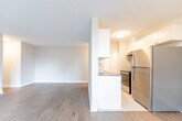 Located at 140 Robinson Street in Hamilton, Ontario, this one-bedroom unit offers a well-organized, single-floor layout designed for comfortable everyday living. Light hardwood flooring runs throughout the space, lending warmth and continuity from room to room.

The open-concept kitchen and living area form the heart of the unit. The kitchen features white cabinetry, dark countertops, a stainless steel sink with a tile backsplash, and a full-size stainless steel refrigerator. A half-wall separates the kitchen from the living area, maintaining an open feel while defining each zone. The living room is generously proportioned, bathed in natural light from a large sliding glass door that opens to a balcony, offering views of the surrounding Hamilton cityscape. An additional window further brightens the space.

The bedroom is a comfortable, well-lit room with a large window overlooking the city, hardwood flooring, and neutral walls that provide a calm, restful atmosphere. The unit's overall palette of soft beige tones and white trim creates a clean, modern aesthetic throughout. With its practical layout, natural light, and urban location, this unit offers a functional and inviting living environment in the heart of Hamilton.