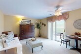 This single-floor, 2-bedroom, 1-bathroom residence offers a practical and comfortable layout across a thoughtfully organized floor plan. The combined living, dining, and kitchen area forms the heart of the home, bathed in natural light from large sliding glass doors that open to an outdoor patio with views of landscaped greenery. A ceiling fan overhead and plush wall-to-wall carpeting contribute to the warm, inviting atmosphere of the living space.

The kitchen is equipped with warm oak cabinetry, ample counter space, and a stainless steel sink, providing efficient functionality. Adjacent dining space allows for easy everyday living and entertaining.

The primary bedroom is generously sized, featuring carpet flooring, a ceiling fan, and natural light from a window. It is accompanied by a spacious walk-in closet with wire shelving, offering abundant storage. A second bedroom provides additional flexibility. The full bathroom is clean and functional, featuring a white vanity with a large mirror, tile flooring, and a shower-tub combination.

Additional highlights include a dedicated laundry room with a full-size washer and dryer, a utility room, a hallway connecting the main spaces, and a total of four closets throughout, ensuring ample storage across the entire residence.