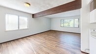 Located at 219 Freedom Dr in Belleville, IL, this 2-bedroom, 1-bathroom residence offers a thoughtfully laid-out single-floor plan. Wood-look laminate flooring runs consistently throughout the entire space, lending a warm and cohesive aesthetic to every room.

The open living room is bright and welcoming, featuring multiple windows with blinds that invite natural light and views of the surrounding greenery. A distinctive wood beam accent adds architectural character to the space. The combined kitchen and living area flows naturally, with the kitchen showcasing dark espresso cabinetry, granite-style countertops, a stainless steel sink, and white appliances including a range, microwave, and refrigerator. A louvered door leads to additional storage or utility access.

Both bedrooms continue the warm flooring theme and are finished with clean white walls, dark-trimmed sliding closet doors, and windows providing natural light. The primary bedroom is generously sized with a large sliding closet, while the second bedroom offers its own closet and window. A hallway connects the rooms efficiently.

The bathroom includes a full tub-shower combination with chrome fixtures and a clean, bright finish. The overall ambiance of the residence is practical yet comfortable, with consistent finishes and neutral tones throughout.