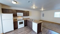 This three-story home provides generous living space spread across multiple levels, offering 4 bedrooms and 4.5 bathrooms to comfortably accommodate residents and guests alike. The kitchen is a functional centerpiece of the home, featuring dark espresso-toned cabinetry that contrasts with light countertops and white appliances, including an electric range, built-in microwave, and dishwasher. A peninsula with an undermount double sink extends the counter space and creates a natural division between the kitchen and the adjacent living area. Durable wood-look flooring runs throughout the kitchen and transitions to carpet in the living space, adding warmth and texture underfoot. Flush-mount ceiling fixtures provide consistent overhead lighting throughout. An electrical panel is conveniently accessible within the space. The open layout between the kitchen and living area promotes an easy flow for daily activities and entertaining. With four full bathrooms and a half bath distributed across three floors, the home offers practical convenience for households of all sizes.