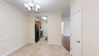 Located at 2001 Village View Cir in Cramerton, NC, this well-designed single-floor home offers three bedrooms, two bathrooms, and a thoughtfully organized layout across a comfortable footprint. The interior is finished with warm, neutral tones throughout, complemented by crown molding and clean white trim that lend a polished, cohesive look to the living spaces.

The dining room flows seamlessly into the kitchen, which features warm wood cabinetry, granite-style countertops, a double stainless steel sink, and black appliances including a refrigerator and range. A pendant light adds a refined touch above the counter, while tile flooring provides a practical surface underfoot. The adjacent dining area is highlighted by an elegant chandelier and chair-rail molding.

The living room offers generous space with hardwood-style flooring and crown molding, opening naturally to the rest of the home through arched passageways. Each of the three bedrooms features the same warm hardwood-style floors and ceiling fans with lighting, with natural light filtering through window blinds. The primary bedroom is a comfortable size with access to closet space.

Both bathrooms are finished with tile flooring, and one includes a full tub-shower combination with brushed nickel fixtures. Additional highlights include a dedicated laundry area with utility connections, three closets for ample storage, and a welcoming hallway connecting the home's rooms.