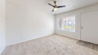 Located at 40 E Sunland Ave in Phoenix, AZ, this two-bedroom, one-bathroom unit offers a thoughtfully arranged single-floor layout. The kitchen is a standout feature, designed in a galley style with white cabinetry, light countertops, and black appliances including a range, refrigerator, and dishwasher. Wood-look flooring runs throughout the kitchen and living area, providing a clean and cohesive aesthetic. The combined kitchen and living room space offers an open, functional flow ideal for daily use. Both bedrooms are finished with plush carpeting and textured ceilings. The primary bedroom is generously sized, featuring a ceiling fan with light fixture, a large window with blinds that allows natural light and outdoor views, and access to a dedicated closet with built-in shelving. The second bedroom also includes a ceiling fan, carpeted flooring, and a window with blinds. The full bathroom is finished with wood-look tile flooring, a white vanity with under-cabinet storage, a wall mirror, and a shower-tub combination. Throughout the unit, a neutral white color palette and clean finishes create a bright, move-in ready atmosphere well-suited for comfortable living in the Phoenix area.