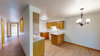 This single-floor space offers a practical and cohesive layout designed for comfortable everyday living. The kitchen is a standout feature, equipped with warm oak cabinetry, light granite-style countertops, white appliances including a coil-top range, dishwasher, and refrigerator, along with a double stainless steel sink. A peninsula counter provides additional workspace and separates the kitchen from the adjoining living and dining areas. The open-concept living and dining space is finished with light wood laminate flooring throughout, and a chandelier adds a touch of character to the dining area. A pass-through window connects the living space to the kitchen, enhancing the open feel of the layout. The bedrooms feature plush carpeting, baseboard heating, and windows that bring in natural light and outdoor views. Two bathrooms are present, each featuring oak vanities with white countertops, large mirrors, and light wood flooring. Warm wood trim and baseboards are consistent throughout the unit, providing a unified aesthetic. The overall ambiance is clean, neutral, and move-in ready, with a straightforward design that prioritizes functionality and livability.