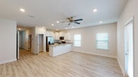 Located in Gulf Breeze, Florida, this two-story, 3-bedroom, 2.5-bathroom home offers a thoughtfully designed layout with modern finishes throughout. The main level features an open-concept living and kitchen area bathed in natural light from multiple windows with white blinds. Light wood-look flooring flows throughout, complementing the neutral, warm-toned walls. The kitchen is well-appointed with crisp white shaker-style cabinetry, granite-look countertops, stainless steel appliances including a French door refrigerator, electric range, and over-the-range microwave, plus a peninsula with a double undermount sink — ideal for both cooking and casual dining. Recessed lighting and a ceiling fan complete the main living space. Upstairs, the bedrooms are generously proportioned with the same light flooring, ceiling fans, and natural light from well-placed windows. The primary bathroom includes a single-sink vanity with stone-look counters and a walk-in shower. A convenient half bath is located on the main level. The home also includes an attached single-car garage with an automatic opener. Clean lines, a neutral palette, and consistent finishes throughout give this home a fresh, move-in-ready feel.