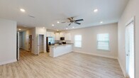 Located in Gulf Breeze, Florida, this two-story, 3-bedroom, 2.5-bathroom home offers a thoughtfully designed layout with modern finishes throughout. The main level features an open-concept living and kitchen area bathed in natural light from multiple windows with white blinds. Light wood-look flooring flows throughout, complementing the neutral, warm-toned walls. The kitchen is well-appointed with crisp white shaker-style cabinetry, granite-look countertops, stainless steel appliances including a French door refrigerator, electric range, and over-the-range microwave, plus a peninsula with a double undermount sink — ideal for both cooking and casual dining. Recessed lighting and a ceiling fan complete the main living space. Upstairs, the bedrooms are generously proportioned with the same light flooring, ceiling fans, and natural light from well-placed windows. The primary bathroom includes a single-sink vanity with stone-look counters and a walk-in shower. A convenient half bath is located on the main level. The home also includes an attached single-car garage with an automatic opener. Clean lines, a neutral palette, and consistent finishes throughout give this home a fresh, move-in-ready feel.