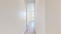 Located at 1145 SW 170th Ave in Beaverton, Oregon, this apartment offers four bedrooms and two full bathrooms across a single, thoughtfully laid-out floor. The contemporary design is defined by crisp white walls, light wood-tone luxury vinyl plank flooring, and tall ceilings that lend an open, airy feel throughout. The combined kitchen and living area serves as the heart of the unit. The kitchen is outfitted with stainless steel appliances—including a range, over-the-range microwave, dishwasher, and refrigerator—complemented by two-tone cabinetry in white and warm wood, subway tile backsplash, and grey countertops. Large windows in the living area flood the space with natural light and provide views of the surrounding neighborhood. The four bedrooms are generously proportioned, each featuring light flooring and clean white walls. The primary bedroom includes access to a dedicated walk-in closet with built-in shelving. Both bathrooms are finished with wood-toned vanities, grey countertops, and full tub-shower combinations with chrome fixtures. Accessibility features such as grab bars are present in one bathroom. The overall aesthetic is modern and neutral, offering a clean canvas well-suited for a variety of living arrangements.