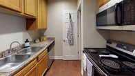 This single-floor residence offers a thoughtfully designed layout with a seamless blend of practicality and comfort. The living area features rich, dark wood-look hardwood flooring, neutral beige walls, and a ceiling fan with light fixture, creating a warm and inviting atmosphere. Vertical blinds along a large sliding door allow for adjustable natural light. The space flows naturally from the living area toward the entryway, which features a solid front door and easy access to adjoining rooms.

The kitchen is efficiently arranged with warm honey-toned cabinetry, granite-style countertops, a stainless steel sink, and black appliances including a range and built-in microwave. Durable wood-look flooring continues throughout this area, adding visual cohesion.

The bedrooms are carpeted for comfort and feature large windows with horizontal blinds that bring in ample natural light. One bedroom offers dual closets, providing exceptional storage capacity. A secondary room with rich hardwood flooring and a bright corner window adds versatility as a bedroom or flex space.

The bathroom includes warm wood cabinetry with a granite-style vanity top, wood-look flooring, and a full bathtub-shower combination. Textured ceilings are consistent throughout, adding a classic finish. Overall, the residence presents a clean, neutral palette well-suited for a variety of living arrangements.