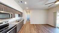 Located in Austin, TX (78754), this thoughtfully designed one-bedroom, one-bathroom unit offers a well-organized single-level layout that maximizes every square foot. Warm wood-look flooring flows throughout, complementing the clean white walls and recessed lighting that keep the space feeling bright and open.

The kitchen is a standout feature, equipped with a full suite of stainless steel appliances — including a refrigerator, range, over-the-range microwave, and dishwasher. Dark-toned cabinetry with sleek bar-pull hardware pairs with granite-style countertops and a white subway tile backsplash, creating a modern, cohesive aesthetic. The kitchen opens directly to the main living area, enhancing the sense of flow.

The bedroom is a comfortable, well-proportioned retreat featuring a ceiling fan, a window with exterior views, and easy access to the bathroom. Its neutral palette and hardwood-style flooring maintain consistency with the rest of the unit.

The bathroom is efficiently appointed with a granite-top vanity, dark cabinetry, a tub/shower combo with white tile surround, a window for natural light, and a stacked in-unit washer/dryer — a highly practical amenity. This unit delivers contemporary finishes and functional design in a compact, well-planned space.