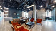 Located at 166 N Aberdeen Street in Chicago's vibrant West Loop neighborhood, this single-floor amenity space blends industrial design with upscale finishes throughout. Exposed black ceiling grids reveal structural ductwork overhead, while polished concrete floors anchor the space with a sleek, contemporary aesthetic.

The main lounge areas are generously proportioned, furnished with tufted leather sofas, curved velvet seating, and mid-century-inspired armchairs in rich terracotta hues. Decorative wall panels with geometric textures and curated artwork add visual depth, while globe pendant lighting and wall sconces provide warm, layered illumination.

Floor-to-ceiling curtain wall windows flood multiple seating zones with natural light and offer direct views of the surrounding Chicago streetscape, with seamless access to an outdoor terrace outfitted with additional seating.

A dedicated conference area features a large communal table beneath dramatic pendant lights, surrounded by expansive glazing on multiple sides. The chef's kitchen is appointed with a wood-topped island, gas cooktop, stainless steel appliances, embossed copper ceiling tiles above the range hood, and patterned tile flooring beneath the bar seating.

A well-equipped fitness center rounds out the floor, offering free weights, strength machines, and cardio equipment on durable rubberized flooring with mirrored walls and ample overhead lighting.