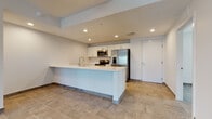 This single-story unit on 25th Street in Sarasota, Florida presents a clean, contemporary design throughout. Large-format stone-look ceramic tile flooring flows consistently across all living areas, lending a cohesive and polished appearance to the space.

The open-concept layout connects the living area directly to the kitchen, which serves as a central feature of the unit. The kitchen is appointed with crisp white cabinetry, light quartz countertops, a full suite of stainless steel appliances including a French door refrigerator, electric range, built-in microwave, and dishwasher. A generous peninsula provides additional prep space and casual seating potential, while recessed lighting overhead keeps the area well-lit.

The living area is bright and spacious, benefiting from multiple windows dressed with blinds that allow natural light control. A sliding glass door with vertical blinds opens to an outdoor view, adding a sense of openness to the interior.

The bathroom features a white vanity with quartz countertop, gold-toned fixtures, a large mirror, and a glass-enclosed walk-in shower with tile surround. The unit's neutral color palette and modern finishes create a clean, move-in-ready atmosphere throughout.