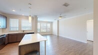 This thoughtfully designed 1-bedroom, 1-bathroom residence offers a comfortable and functional single-floor layout. The open-concept living, dining, and kitchen area serves as the heart of the home, featuring warm hardwood-style flooring, crown molding, and a ceiling fan that enhance the bright and airy atmosphere. Multiple windows dressed with horizontal blinds invite abundant natural light throughout the space.

The modern kitchen is a standout feature, boasting dark wood cabinetry, a large white-topped island with pendant lighting overhead, and a full suite of stainless steel appliances including a refrigerator, range, microwave, and dishwasher. The living and dining areas flow seamlessly from the kitchen, offering ample room for entertaining and everyday living.

The bedroom is generously sized, finished with plush carpet, two windows with natural light, a ceiling fan, and convenient access to a spacious walk-in closet with built-in shelving. The full bathroom features a tiled tub-shower combination with stylish marble-look tile surround, brushed nickel grab bars, and coordinating tile flooring. A hallway connects all areas of the home cohesively, completing this well-organized and move-in-ready residence.