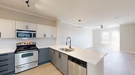 Located at 3820 W Northwest Hwy in Dallas, TX, this well-appointed one-bedroom, one-bathroom residence offers a thoughtfully designed open-concept layout finished with light wood-style flooring and crown molding throughout. The kitchen is a standout feature, boasting two-tone cabinetry — white upper cabinets paired with slate-blue lower cabinets — complemented by crisp white quartz countertops, a stainless steel sink with a modern pull-down faucet, and a full suite of stainless steel appliances including a refrigerator, electric range, microwave, and dishwasher. A peninsula counter seamlessly connects the kitchen to the combined dining and living area, which benefits from natural light and a ceiling fan. The spacious primary bedroom features a ceiling fan, a window with outdoor views, and direct access to the bathroom and closet. The bathroom is outfitted with a wide vanity topped with light quartz countertops, a large framed mirror, and modern fixtures. A dedicated walk-in closet provides ample storage. Neutral warm-gray walls and consistent flooring tie the entire space together, creating a clean, modern, and cohesive living environment.