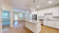 Located at 7045 Pine Forest Rd in Pensacola, Florida, this single-story, 2-bedroom, 2-bathroom home offers a well-designed open-concept layout with modern finishes throughout. The combined kitchen and living area serves as the heart of the home, featuring light hardwood-style flooring, recessed lighting, and ceiling fans. The kitchen is outfitted with crisp white shaker cabinetry, a white subway tile backsplash, granite countertops, a center island with pendant lighting, and a full suite of stainless steel appliances. Natural light flows in through multiple windows dressed with blinds, complementing the bright, neutral color palette. The living area offers an easy transition to an exterior door, enhancing the open feel of the space. Both bedrooms are carpeted and generously proportioned, with the primary bedroom featuring dual windows and a ceiling fan. Each bedroom benefits from dedicated closet space. The bathrooms mirror the kitchen's modern aesthetic, showcasing white vanities with granite countertops, large mirrors with lighted fixtures, and glass-enclosed showers. The primary bathroom includes a walk-in closet with built-in shelving. Clean lines, consistent finishes, and abundant natural light give this home a bright, move-in-ready appeal.