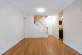 This two-bedroom, two-storey home in Oshawa, ON offers a functional and comfortable layout spread across two well-proportioned floors. The main level features a bright living room with warm hardwood flooring, large sliding glass doors that invite natural light and provide views of the outdoor surroundings, and baseboard heating throughout. The galley-style kitchen is well-appointed with white cabinetry, grey laminate countertops, stainless steel appliances including a refrigerator, stove, microwave, and dishwasher, and a double stainless steel sink. A dedicated dining area completes the main living space. A classic wood-railed staircase leads to the upper level, where two bedrooms are located. The spacious primary bedroom features distinctive parquet hardwood flooring and a sliding double-door closet, while the second bedroom also showcases parquet flooring and a textured ceiling. The full bathroom includes a soaker tub with shower, vanity, and tile surround. A dedicated laundry room houses a full-size washer and dryer alongside a utility sink and water heater. Neutral tones and hardwood flooring throughout give the home a clean, cohesive aesthetic.