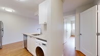 This efficiently designed one-bedroom, one-bathroom unit offers a thoughtful layout across a single floor, making excellent use of its compact footprint. Warm hardwood flooring flows consistently throughout the space, lending a cohesive and inviting feel to every room.

The open living area is bright and airy, anchored by a large sliding glass door that opens onto a private balcony with sweeping urban skyline views. This seamless indoor-outdoor connection allows abundant natural light to fill the room.

The galley-style kitchen is well-equipped with white shaker cabinetry, granite-look countertops, a classic subway tile backsplash, and a full suite of stainless steel appliances including a refrigerator, electric range with microwave, and dishwasher. A practical in-unit washer is also integrated into the kitchen area, adding everyday convenience.

The bedroom is a comfortable and well-proportioned retreat, featuring a large window framing city views, a built-in closet with ample shelving and hanging space, and baseboard heating. A connecting hallway leads to the full bathroom, which is finished with white subway tile surrounding the bathtub and shower, a granite-topped vanity with an undermount sink, and clean white cabinetry. The overall design is clean, modern, and move-in ready.