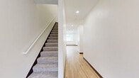 This well-designed two-story home in Rochester, Minnesota offers three bedrooms and three full bathrooms across two thoughtfully laid-out floors. The main level features an open-concept kitchen and living area with warm, light-toned hardwood-style flooring throughout. The kitchen is appointed with crisp white shaker cabinetry extending to the ceiling, light quartz countertops, a central island with pendant lighting, and a full suite of stainless steel appliances including a refrigerator, range, built-in microwave, and dishwasher. The living room is anchored by a sleek, modern linear fireplace set into a clean white surround, complemented by recessed lighting and a window that brings in natural light. A dedicated laundry room on the main level provides added convenience with full-size washer and dryer hookups and hardwood-style flooring. The upper floor houses all three bedrooms, each finished with plush neutral carpet, ceiling fans, and ample closet space. The generously sized primary bedroom includes its own walk-in closet. The three bathrooms offer a clean, modern aesthetic with light wood-tone flooring, white vanities, and a mix of tub/shower combos and a walk-in shower, all finished with brushed nickel fixtures.