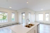 Located at 14009 28 Avenue SW in Edmonton, Alberta, this well-appointed 2-bedroom, 3-bathroom residence offers a thoughtfully designed single-floor layout with a clean, contemporary aesthetic throughout. Light-toned hardwood-style flooring flows seamlessly through every room, complementing the bright, neutral palette of warm white walls and crisp trim.

The open-concept kitchen and living area serves as the heart of the home, featuring white shaker-style cabinetry, a subway tile backsplash, a central island with an integrated sink, and a full suite of stainless steel appliances. Recessed lighting and a wall-mounted air conditioning unit add both functionality and a modern touch. The living area extends toward a glass-railed balcony, offering pleasant views of the surrounding landscaped neighborhood.

The bedrooms are generously proportioned, each filled with natural light through large windows overlooking the street and greenery outside. The primary bedroom offers a comfortable retreat with access to its own dedicated bathroom. The three bathrooms are finished in a consistent modern style, with one featuring a full soaker tub and shower combination with clean white tile surround. A dedicated closet provides additional storage. Baseboard heating runs throughout, ensuring year-round comfort in this efficiently designed home.