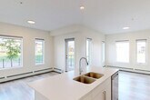 Located at 14009 28 Avenue SW in Edmonton, Alberta, this well-appointed 2-bedroom, 3-bathroom residence offers a thoughtfully designed single-floor layout with a clean, contemporary aesthetic throughout. Light-toned hardwood-style flooring flows seamlessly through every room, complementing the bright, neutral palette of warm white walls and crisp trim.

The open-concept kitchen and living area serves as the heart of the home, featuring white shaker-style cabinetry, a subway tile backsplash, a central island with an integrated sink, and a full suite of stainless steel appliances. Recessed lighting and a wall-mounted air conditioning unit add both functionality and a modern touch. The living area extends toward a glass-railed balcony, offering pleasant views of the surrounding landscaped neighborhood.

The bedrooms are generously proportioned, each filled with natural light through large windows overlooking the street and greenery outside. The primary bedroom offers a comfortable retreat with access to its own dedicated bathroom. The three bathrooms are finished in a consistent modern style, with one featuring a full soaker tub and shower combination with clean white tile surround. A dedicated closet provides additional storage. Baseboard heating runs throughout, ensuring year-round comfort in this efficiently designed home.