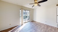Located at 7502 Hunt Club Rd in Columbia, SC, this single-floor, 2-bedroom, 1-bathroom home offers a practical and comfortable layout. Wood-look plank flooring flows throughout the main living areas, lending a cohesive, clean aesthetic. The galley-style kitchen is a standout feature, showcasing rich dark cabinetry with ample storage, white countertops, and a full suite of black appliances including a refrigerator, range, microwave, and dishwasher. A flush-mount light fixture brightens the space, and the layout allows for efficient meal preparation. The living room is bright and airy, benefiting from a sliding glass door that opens to an outdoor balcony, framing views of the surrounding greenery. A ceiling fan adds comfort and functionality to this room. The primary bedroom features wood-look flooring, a built-in closet, and direct sightlines to the bathroom, which is finished with wood-look tile, a tub-shower combination with white subway tile surround, and brushed nickel hardware. The secondary bedroom is carpeted and includes a window with natural light. Textured ceilings are present throughout, and crisp white walls create a neutral backdrop across all rooms.
