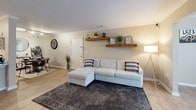 Located at 1001 River Haven Circle in Charleston, SC, this single-story home presents a well-designed, open-concept layout finished with warm neutral tones and light wood-style flooring throughout. Crown molding accents the main living areas, adding a refined touch to the relaxed coastal aesthetic.

The living room is generously proportioned, featuring rustic floating wood shelves, a sectional seating area, and large windows that invite natural light. A dedicated sunroom-style nook extends the living space further, offering a bright retreat.

The kitchen is a standout feature, outfitted with crisp white cabinetry, granite countertops, a deep stainless steel sink, and a full suite of stainless steel appliances including a range, microwave, and refrigerator. A breakfast bar with barstool seating connects the kitchen to the main living area.

The primary bedroom is spacious and comfortable, equipped with a ceiling fan and natural light from a window with decorative curtains. A walk-in closet with wire shelving provides functional storage. Additional bedrooms are well-sized, each with hardwood-style flooring and natural light. The bathroom features granite vanity surfaces and wood-look tile flooring, maintaining the consistent design language found throughout this thoughtfully finished Charleston home.