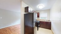 Located at 2010 Drexel St in Hyattsville, MD, this single-floor, 2-bedroom, 1-bathroom residence offers a practical and well-appointed layout. Warm hardwood flooring flows throughout the living areas and bedrooms, lending a cohesive and inviting character to the home. The living room is bright and open, with natural light streaming in through a large window that frames outdoor greenery, and is complemented by a baseboard radiator for heating. The kitchen is efficiently designed with rich dark cabinetry extending to the ceiling for ample storage, granite-toned countertops, a stainless steel refrigerator, and a gas range — all finished with tile flooring. Both bedrooms feature the same gleaming hardwood floors, neutral gray walls, and windows with outdoor views. The bedrooms are supported by generous closet space, with four closets distributed throughout the unit. The bathroom is neatly finished with full-height beige ceramic tile surrounding the shower and tub combination, accented by a decorative mosaic tile border, and includes a window for natural light and ventilation. A connecting hallway ties the spaces together, completing this functional and comfortable Hyattsville home.