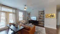 This single-story residence offers two bedrooms and two bathrooms within a thoughtfully designed open floor plan. The living room features rich hardwood-style flooring, a ceiling fan, and a large window that invites natural light, creating a warm and welcoming atmosphere. Open-frame shelving units flank a media console, adding both storage and visual interest. Adjacent to the living area, a dedicated dining space accommodates a full-size table, making it well-suited for entertaining.

The kitchen is a standout feature, equipped with stainless steel appliances, dark espresso cabinetry, and a quartz-topped island with seating for two, illuminated by globe pendant lights. The layout connects seamlessly to the entry foyer.

The primary bathroom features an elongated double-vanity with quartz countertops and dark cabinetry, providing generous storage. The secondary bathroom offers a full tub-shower combination with clean white tile. Both bedrooms include carpeted flooring and closet space. One bedroom functions as a versatile office or guest room, with a large window overlooking outdoor surroundings. Throughout, the design balances modern aesthetics with functional, comfortable living.
