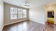 Located at 1980 Icon Way in Knoxville, TN, this one-bedroom, one-bathroom unit offers a well-designed, single-floor layout with modern finishes throughout. Wood-style flooring flows consistently across every room, complementing the neutral, warm-toned walls that create a clean and cohesive aesthetic.

The open-concept kitchen and living area serves as the heart of the unit. The kitchen is outfitted with crisp white shaker-style cabinetry, a white subway tile backsplash, quartz countertops, a large kitchen island with a built-in sink, pendant lighting, and a full suite of stainless steel appliances including a refrigerator with ice maker, range, microwave, and dishwasher. Double pantry doors provide ample storage.

The living area extends naturally from the kitchen, bathed in natural light from a bank of windows overlooking the surrounding neighborhood. A ceiling fan adds comfort to the space.

The primary bedroom is generously proportioned, featuring windows with exterior views, a ceiling fan, and direct access to the walk-in closet, which is equipped with wire shelving systems for organized storage.

The bathroom is notably spacious, boasting a long dual-sink vanity with quartz countertops, backlit mirrors, and a glass-enclosed walk-in shower, with direct access to the walk-in closet beyond.