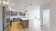 This well-designed 3-bedroom, 2-bathroom home in the Waterton Canyon community of Littleton, Colorado offers a thoughtful single-floor layout with modern finishes throughout. The open-concept kitchen and living area serves as the heart of the home, featuring sleek gray shaker cabinetry, a subway tile backsplash, white quartz countertops, stainless steel appliances, and a generous center island illuminated by a trio of brushed nickel pendant lights. Light hardwood flooring flows seamlessly through the main living spaces, enhancing the bright, airy ambiance. The spacious primary bedroom features plush carpeting, a ceiling fan, and direct access to a private ensuite bathroom. Two additional bedrooms offer comfortable accommodations, each with soft carpet and windows that bring in natural light. Both bathrooms are finished with gray vanities, white countertops, and tiled tub-shower combinations with brushed nickel hardware. A walk-in closet provides ample storage, while an in-unit stacked washer and dryer adds everyday convenience. The living area benefits from large windows offering views of the surrounding neighborhood. Clean white walls and consistent modern finishes give the entire home a cohesive, contemporary feel.