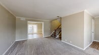 Located in Murfreesboro, Tennessee, this two-story home offers a practical and well-organized layout across two floors. The main level features a welcoming entrance that opens into a carpeted living room, where a wood-banistered staircase adds a classic architectural touch. Adjacent to the living room, the dining room benefits from natural light streaming through French doors, and is accented by a chandelier overhead. The main floor also includes hard surface flooring in key areas, crown molding details, and a half bathroom finished with light wood-look flooring. Upstairs, three bedrooms provide comfortable accommodations, each featuring plush carpet, ceiling fans, and built-in closets with bi-fold doors. The spacious primary bedroom is particularly notable, featuring dual windows that fill the room with natural light and elegant crown molding. Two additional bedrooms on the upper level offer ample space and closet storage. The home includes three full bathrooms and a dedicated laundry area with utility connections already in place. Neutral warm-beige tones throughout create a cohesive, move-in-ready aesthetic. With two kitchen spaces and a thoughtful room count, this home suits a variety of living arrangements in a convenient Murfreesboro location.