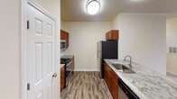 Located at 221 Embassy Dr in Fort Mill, SC, this single-floor residence offers a thoughtfully designed layout with a clean, neutral aesthetic throughout. The open-concept living and dining area flows seamlessly into the kitchen, which is equipped with rich cherry wood cabinetry, granite countertops, stainless steel appliances including a range, microwave, refrigerator, and dishwasher, and durable wood-look flooring. A breakfast bar peninsula provides additional workspace and casual seating. Crown molding accents the living area, adding a refined architectural touch. The bedrooms are carpeted for comfort and feature ceiling fans with light fixtures, windows with blinds that allow natural light while maintaining privacy, and views of the surrounding neighborhood. The bathrooms are well-appointed with cherry wood vanities, granite countertops, brushed nickel fixtures, and a combination shower and tub. The overall color palette of warm cream and beige tones creates a bright and welcoming atmosphere throughout the home. The space is characterized by a practical single-level floor plan with clear sight lines between the main living areas, making it functional and easy to navigate.