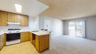 Located at 1225-1237 Graves Ave in El Cajon, California, this single-story unit presents a practical and functional layout designed for comfortable everyday living. The kitchen is well-equipped with warm oak-toned cabinetry spanning both upper and lower configurations, offering generous storage throughout. A full suite of appliances includes a white refrigerator, electric range, and dishwasher. Tile flooring runs through the kitchen, which connects to the living area via a peninsula counter with a built-in sink, creating an open and communicative flow between spaces. The living area is carpeted and spacious, featuring a ceiling fan and a textured ceiling finish consistent throughout the unit. Natural light filters in through windows and a sliding door that leads to a balcony, adding an outdoor connection to the main living space. A separate room off the main area provides additional flexible space, also finished with carpet and a textured ceiling. The bathroom is clean and straightforward, featuring a tub-shower combination, toilet, and an oak-finished overhead cabinet for storage, with tile flooring completing the space. The unit's neutral color palette and consistent finishes give it a cohesive, understated character throughout.