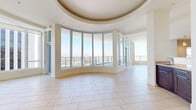 Located in the heart of downtown Phoenix at 44 W Monroe St, this sophisticated high-rise residence offers three bedrooms, five bathrooms, and generous living space spread across a single floor. The open-concept living room is an architectural showpiece, defined by a dramatic curved wall of floor-to-ceiling windows that frame sweeping panoramic views of the Phoenix skyline and surrounding mountains. A distinctive recessed tray ceiling adds elegance to the living area, while large-format tile flooring flows throughout the main living spaces. The gourmet kitchen is outfitted with rich dark wood cabinetry, granite countertops, stainless steel appliances including a professional-grade gas range and wall oven, and a tasteful tile backsplash. The spacious primary bedroom suite offers plush carpet, a generous picture window with city views, and ample closet space with built-in shelving. Additional bedrooms are well-proportioned and share access to well-appointed bathrooms. A dedicated laundry room houses a full-size washer and dryer with overhead shelving. The expansive private balcony, accessible from the living area, provides breathtaking elevated views of downtown Phoenix and the distant mountain ranges — an exceptional outdoor retreat above the city.