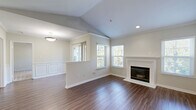 Located at 5925 Highdale Circle in Alexandria, Virginia, this well-appointed one-bedroom, one-bathroom residence offers a thoughtfully designed single-floor layout with a welcoming sense of space. The open-concept living and dining area immediately impresses with vaulted ceilings, rich hardwood-style flooring, crown molding, and classic wainscoting panels. A white-mantled fireplace serves as the room's focal point, flanked by multiple windows that bathe the space in natural light and offer serene, tree-lined outdoor views. A private balcony extends the living area outdoors, overlooking a lush, landscaped greenspace. The kitchen features sleek gray cabinetry, white countertops, stainless steel appliances including a range, built-in microwave, and refrigerator, and connects seamlessly to the dining area via a pass-through window. The bedroom is carpeted and generously sized, offering tranquil views through large windows with blinds. The full bathroom includes a gray vanity with ample storage, a large mirror, and a tub-shower combination with hardwood-style flooring. Three closets provide exceptional storage throughout. An in-unit laundry area with a full-size washer and dryer adds everyday convenience, completing this polished and functional Alexandria residence.