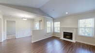 Located at 5925 Highdale Circle in Alexandria, Virginia, this well-appointed one-bedroom, one-bathroom residence offers a thoughtfully designed single-floor layout with a welcoming sense of space. The open-concept living and dining area immediately impresses with vaulted ceilings, rich hardwood-style flooring, crown molding, and classic wainscoting panels. A white-mantled fireplace serves as the room's focal point, flanked by multiple windows that bathe the space in natural light and offer serene, tree-lined outdoor views. A private balcony extends the living area outdoors, overlooking a lush, landscaped greenspace. The kitchen features sleek gray cabinetry, white countertops, stainless steel appliances including a range, built-in microwave, and refrigerator, and connects seamlessly to the dining area via a pass-through window. The bedroom is carpeted and generously sized, offering tranquil views through large windows with blinds. The full bathroom includes a gray vanity with ample storage, a large mirror, and a tub-shower combination with hardwood-style flooring. Three closets provide exceptional storage throughout. An in-unit laundry area with a full-size washer and dryer adds everyday convenience, completing this polished and functional Alexandria residence.